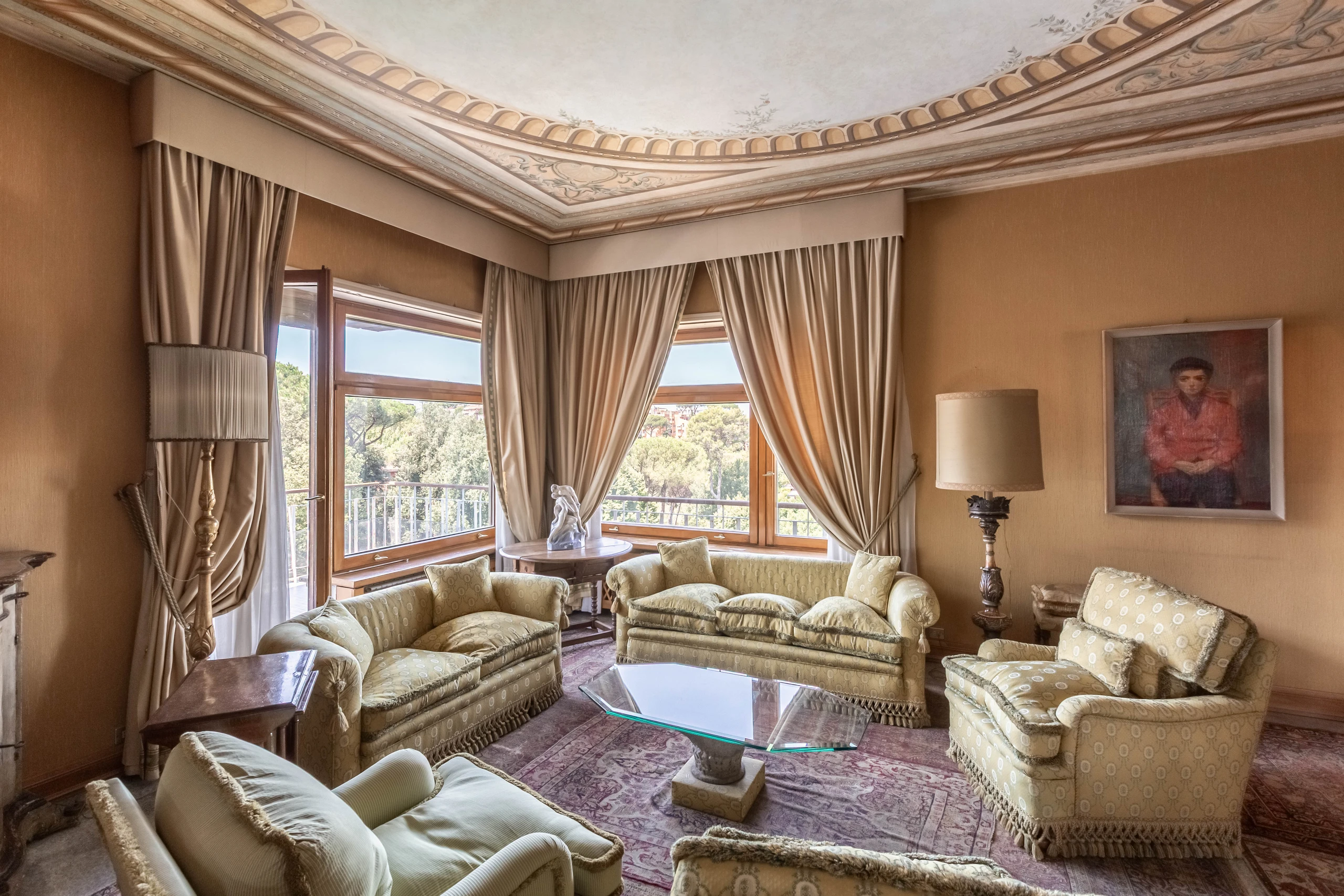Salone classico con soffitto decorato e ampie finestre affacciate sugli alberi